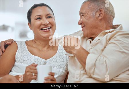 Détendez-vous, couple de personnes âgées et café dans un salon avec des aînés heureux, souriants et paisibles qui embrassent dans leur maison. Retraite, thé et pause avec Banque D'Images