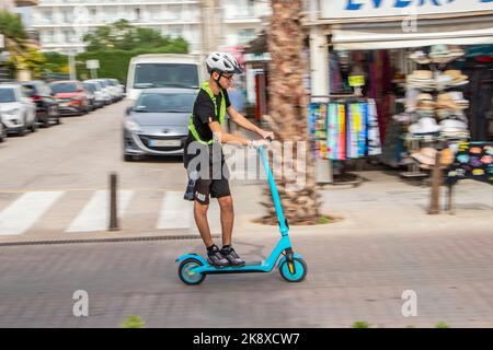 plan panoramique d'un jeune homme sur un scooter électrique sur la promenade du front de mer à can pastilla mallorca espagne Banque D'Images