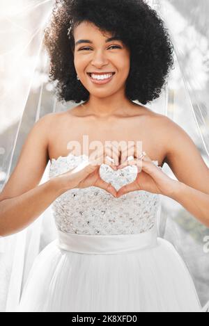 Célébraient le vrai amour aujourd'hui. Portrait d'une jeune mariée heureuse et belle en forme de coeur avec ses mains à l'extérieur le jour de son mariage. Banque D'Images