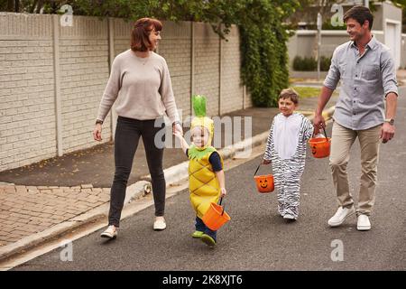 Allons faire peur aux voisins. Photo en plein écran d'un adorable petit tour de famille ou de se faire dorer ensemble dans le quartier lors de l'halloween. Banque D'Images