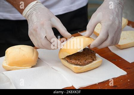 L'Italie, Lombardie, Street Food, main d'un chef Holding une saucisse Banque D'Images