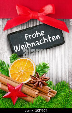 Décoration et étiquette de Noël joyeuse allemande avec étoiles, branches de cannelle et de sapin sur fond de bois Banque D'Images