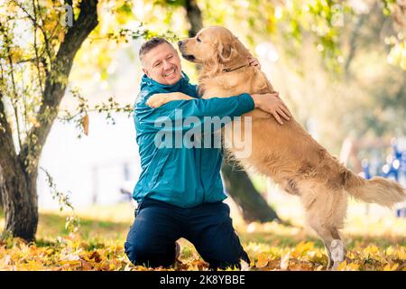 Homme jouant avec son chien Golden Retriever dans le parc Banque D'Images