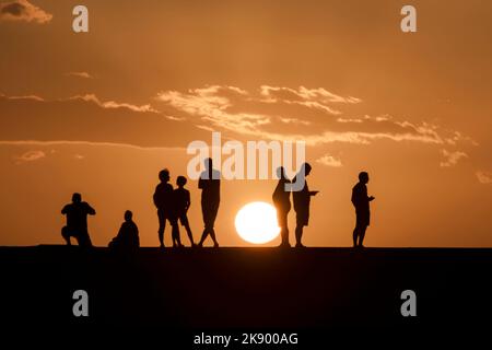 Silhouettes d'un groupe de personnes regardant le coucher du soleil au phare de Maspalomas, Maspalomas, Gran Canary, îles Canaries, Espagne Banque D'Images