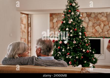 Maintenant étaient officiellement prêts pour Noël. Vue arrière d'un couple adulte méconnu assis ensemble sur un canapé se tenant l'un contre l'autre tout en regardant Banque D'Images