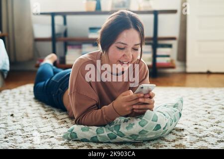 Moi, moi et mon fil d'actualité. Une jeune femme utilisant un smartphone tout en se relaxant à la maison. Banque D'Images