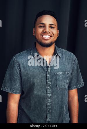 Sourire ma façon d'entrer dans la nouvelle année. Portrait court d'un beau jeune homme debout seul sur fond sombre dans le studio. Banque D'Images