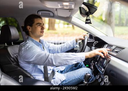 gros plan du jeune homme en costume de voiture de conduite et d'allumer un bouton sur le panneau de voiture Banque D'Images