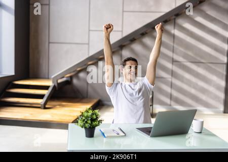 Homme heureux gagnant euphorique à l'aide d'un ordinateur portable dans un bureau à la maison Banque D'Images