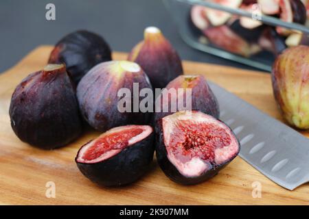 figues fraîches juteuses sur une planche à découper en bois Banque D'Images