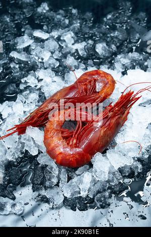 Un cliché vertical de crevettes rouges fraîches crues sur la glace sur un marché Banque D'Images