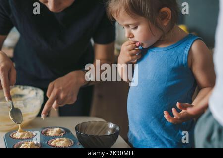 La plaque de cuisson pleine de papier coloré se remplit de pâte à muffins, prête à cuire. Forme la pâte crue de muffin. Mets sucrés Banque D'Images