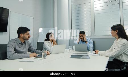 Un jeune patron arabe mécontent, colant des employés pour de mauvais travaux lors de réunions de divers groupes, un chef d'équipe en colère tenant la tête réprimante Banque D'Images