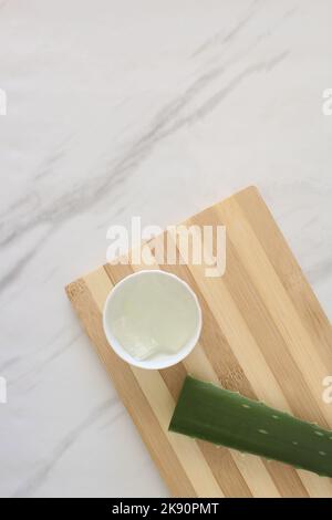 Morceaux de vera d'aloès et un bol de gel de vera d'aloès sur la planche à découper. Banque D'Images