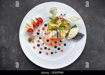 Tartare de boeuf avec asperges et tomates sur une assiette, sur fond sombre Banque D'Images