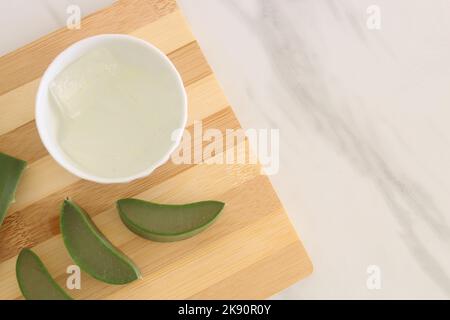 Morceaux de vera d'aloès et un bol de gel de vera d'aloès sur la planche à découper. Banque D'Images