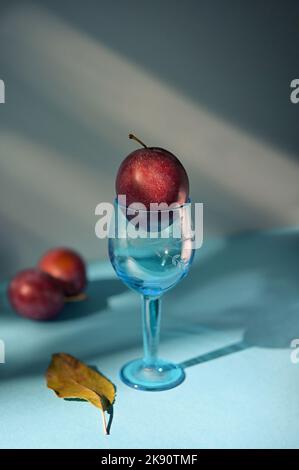 Prunes mûres abstraites en petit verre pousse en studio Banque D'Images