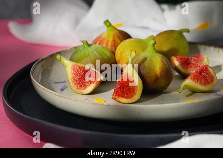 Figues fruits placés sur une petite assiette sur une table avec une nappe et le soleil Banque D'Images