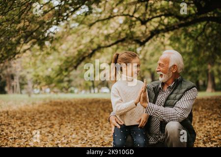 Beau grand-père passant du temps avec sa petite-fille dans le parc le jour de l'automne Banque D'Images