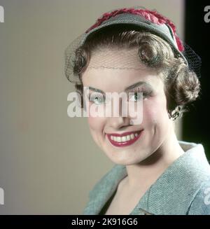 Dans le 1950s. Portrait d'une femme portant un chapeau à la mode, un maquillage coloré et décorateurs dans ses cheveux que les lumières hautes sur le côté et brille festivement. Suède 1958 réf. CV83 Banque D'Images