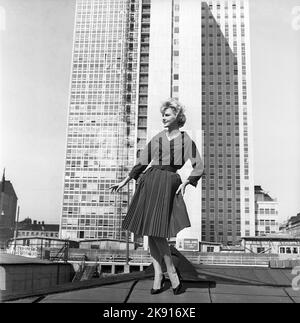 Dans le 1950s. Une femme qui se moque d'une tenue de 1950s avec une veste et une jupe dans le noir assorti. En arrière-plan, le gratte-ciel récemment terminé abrite les bureaux fiscaux suédois. Suède 1959 Kristoffersson réf. CH21 Banque D'Images