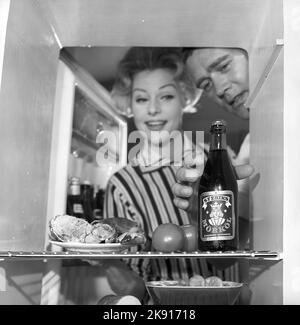 Dans la cuisine 1950s. Un couple dans leur cuisine et au réfrigérateur où la nourriture et la bière sont conservées. Suède 1959. Kristoffersson réf. CH77-7 Banque D'Images