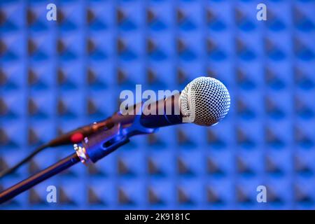 Mise au point douce du microphone professionnel monté sur le support contre un mur insonorisé bleu dans le studio d'enregistrement Banque D'Images