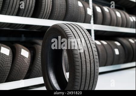 Nouveau pneu noir de voiture neuf sur le plancher près du comptoir de la pile avec des pneus dans un magasin moderne Banque D'Images