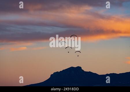 Quatre parapentes propulsés volent en formation au coucher du soleil près de Hanksville, Utah. Banque D'Images