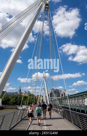 Golden Jubilee Bridge à côté du pont ferroviaire Hungerford au-dessus de la Tamise, Londres, Royaume-Uni. Les gens qui traversent le pont piétonnier avec des câbles Banque D'Images