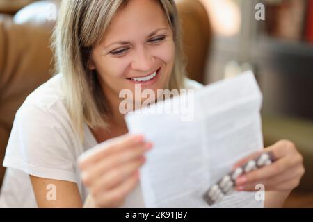 Femme souriante lisant des instructions pour l'utilisation médicale de pilules Banque D'Images