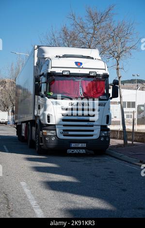 Une verticale de camion blanc Scania R440 avec des rideaux rouges garés dans la rue. Banque D'Images