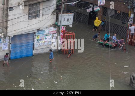 Les propriétaires de pousse-pousse ont du mal à traverser une rue engortée à la suite de fortes pluies qui causent beaucoup de souffrances aux piétons et aux navetteurs. Le cyclone Sitrang frappe le Bangladesh en train d'établir des liaisons de communication et d'alimentation, inondant les rues pour faire encore des activités. Banque D'Images