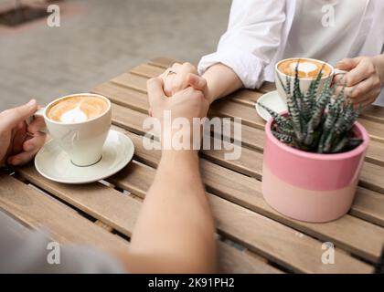 Couple tenant les mains et le café à l'extérieur, vue latérale du dessus. Banque D'Images