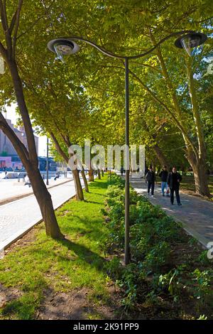 Lampadaire dans un parc avec des personnes marchant en arrière-plan. Pôle lumineux avec deux lampes LED dans un parc vert. Banque D'Images