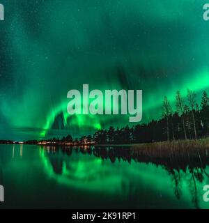 Spectaculaire photo de nuit fortes lumières vertes de danse Aurora sur la forêt du Nord, réflexion dans le lac, petit bateau, pont. Lac Stocksjo, nord-ouest Banque D'Images