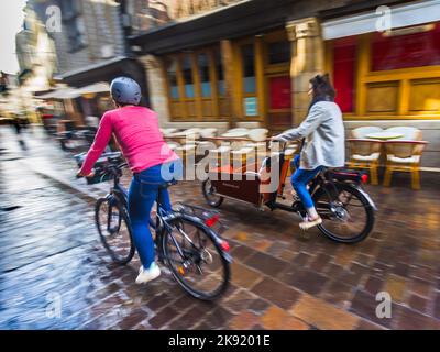 Deux femmes en vélo à travers le vieux quartier de Tours, Indre-et-Loire (37), France. Banque D'Images