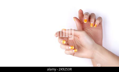 De belles mains féminines avec une manucure orange vif comme le maïs Candy sur fond blanc. Ongles manucurés avec Creative Gel Polish Design. Halloween STY Banque D'Images