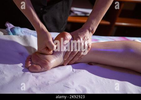 Goias, Brésil – 01 octobre 2022 : détail des mains d'un massothérapeute massant la semelle du pied d'un patient, à l'aide d'huile essentielle. Banque D'Images