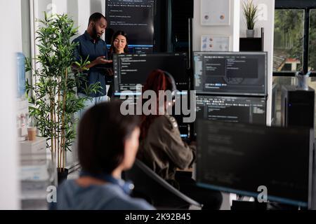 Programmeurs de logiciels discutant des algorithmes sur grand écran et ordinateur portable, analysant le langage de code html. Une équipe d'ingénieurs système s'intéresse à la base de données sur la fenêtre du terminal, l'interface du serveur. Banque D'Images