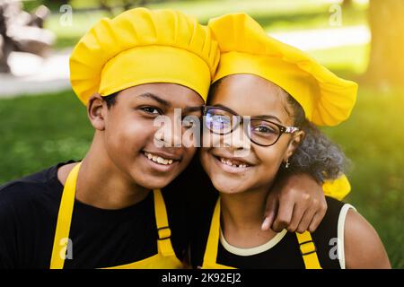 Les enfants africains cuisinent dans les chefs chapeau et uniformes jaunes souriant portrait de près . L'adolescent africain et la fille noire ont du plaisir et cuisent la nourriture Banque D'Images