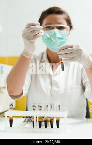 Analyse du plasma sanguin. L'assistant de laboratoire tient un tube à essai avec du sang d'une veine dans ses mains et le regarde. Test sanguin en laboratoire Banque D'Images