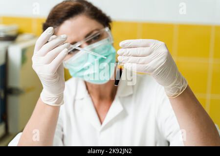 Analyse du plasma sanguin. L'assistant de laboratoire tient un tube à essai avec du sang d'une veine dans ses mains et le regarde. Test sanguin en laboratoire Banque D'Images