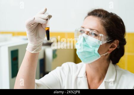 Analyse du plasma sanguin. L'assistant de laboratoire tient un tube à essai avec du sang d'une veine dans ses mains et le regarde. Test sanguin en laboratoire Banque D'Images