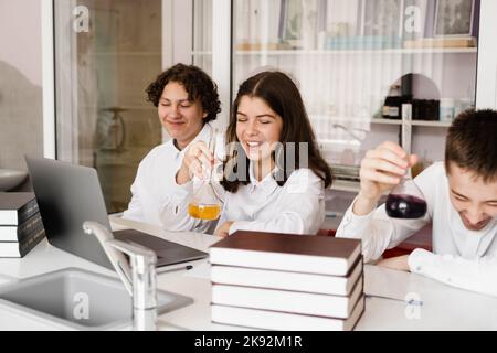 Pupilles contenant des flacons avec liquide pour des expériences en laboratoire. Concept d'éducation. Groupe d'élèves étudiant la leçon de chimie à l'école Banque D'Images