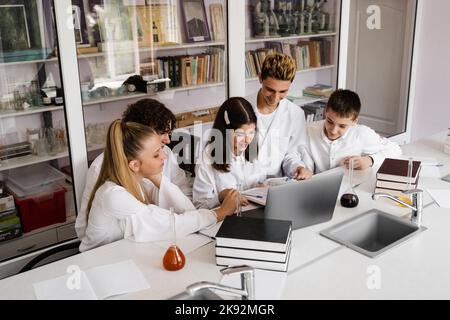 La classe étudie dans la leçon de chimie à l'école dans le laboratoire. Éducation. L'enseignant vérifie les devoirs dans le livre. Préparation de l'exper Banque D'Images