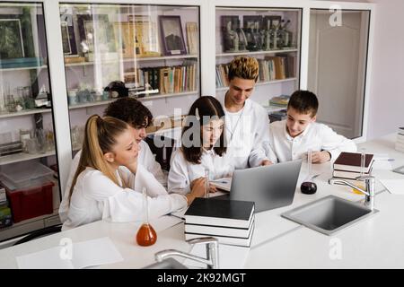 La classe étudie dans la leçon de chimie à l'école dans le laboratoire. Éducation. L'enseignant vérifie les devoirs dans le livre. Préparation de l'exper Banque D'Images