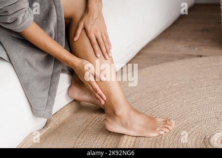 Thrombose veineuse profonde et varices de la femme africaine. Fille touchant ses jambes et regardant les veines. Procédure de sclérothérapie chez un chirurgien vasculaire en visite Banque D'Images