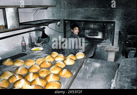 ANKARA,TURQUIE - DEC 29, 1985: L'enfant dans la boulangerie cuit du pain frais dans l'ancien four à Ankara, Turquie. Banque D'Images
