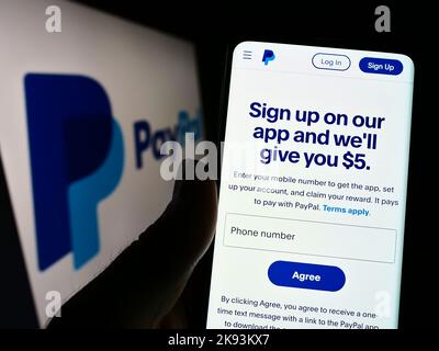 Personne tenant un téléphone portable avec la page Web de la société financière américaine PayPal Holdings Inc. À l'écran devant le logo. Concentrez-vous sur le centre de l'écran du téléphone. Banque D'Images